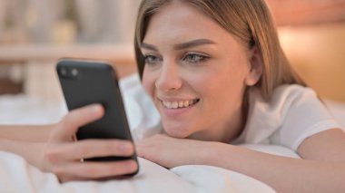 Yatakta Smartphone kullanan Mutlu Genç Kadın 'a yaklaş