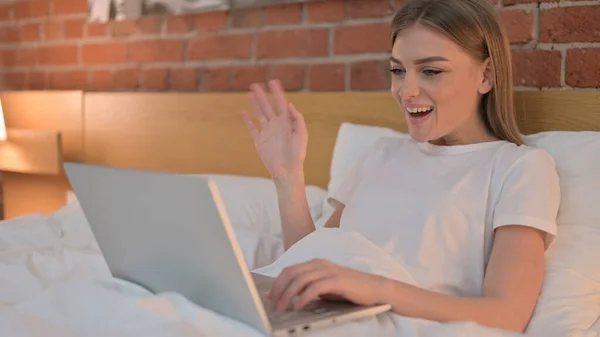 Jovem alegre do sexo feminino fazendo vídeo chat no laptop na cama — Fotografia de Stock
