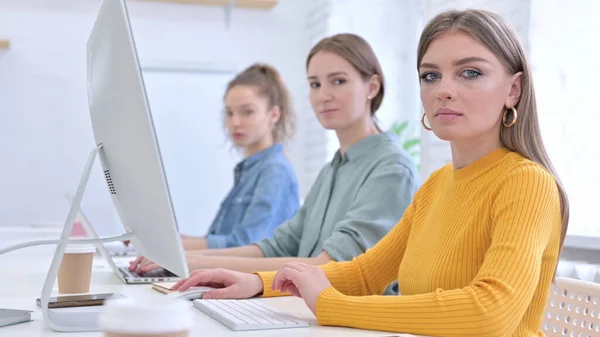 Jeune équipe créative travaillant sur Desktop et regardant la caméra — Photo