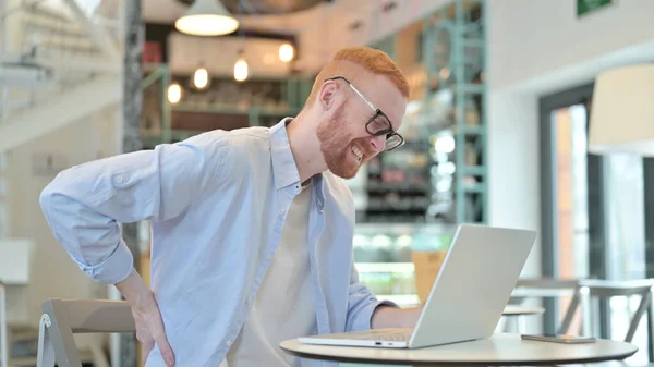 Homme rousse avec douleur au dos à l'aide d'un ordinateur portable dans Cafe — Photo