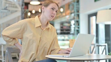 Kafede dizüstü bilgisayar kullanan Sırt Ağrısı Olan Genç Kadın