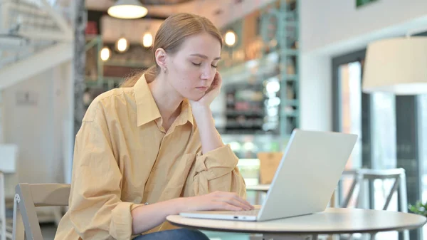 在咖啡店用笔记本电脑打盹的年轻女人 — 图库照片