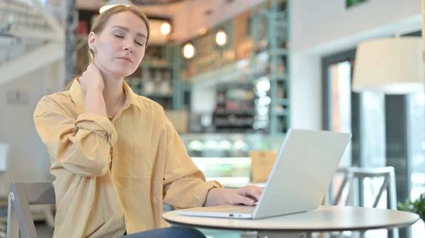 咖啡中使用笔记本电脑的年轻女性颈部疼痛 — 图库照片