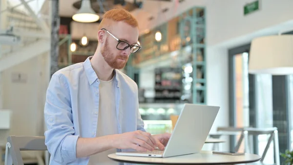 Professionele roodharige man met behulp van laptop in Cafe — Stockfoto