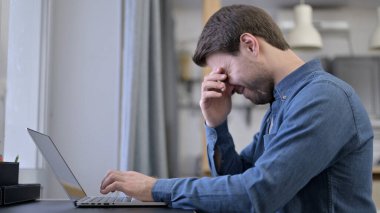 Young Man having Headache on Laptop