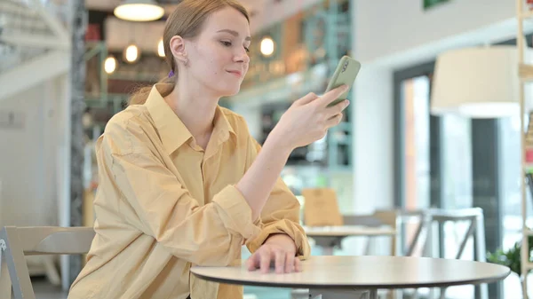Mujer joven Desplazamiento en Smartphone en Café — Foto de Stock