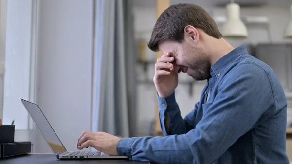 Jeune homme ayant mal à la tête sur ordinateur portable — Photo