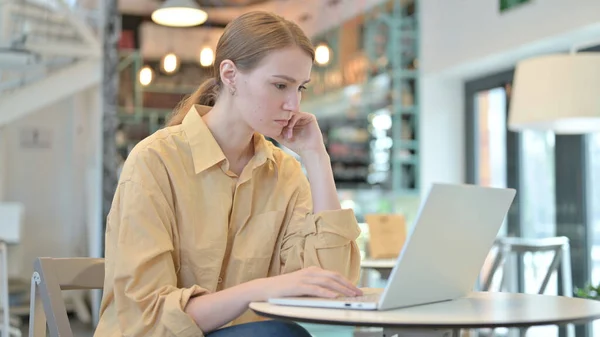 在咖啡馆里用笔记本电脑思考的年轻女人，头脑风暴 — 图库照片