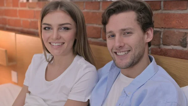 Retrato de alegre jovem casal sorrindo para a câmera da cama — Fotografia de Stock