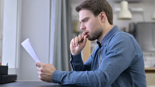 Ung man läser dokument i Office — Stockfoto