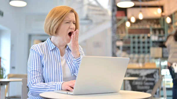 Uso del computer portatile da sbadigliare creativo vecchia donna in Cafe — Foto Stock