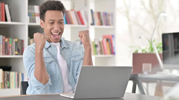 Young African American Man Celebrating Success on Laptop