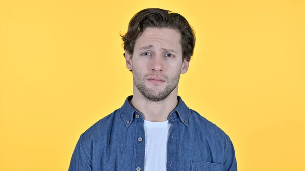 Orolig ung man på gul bakgrund — Stockfoto