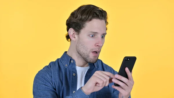 Young Man with Loss on Smartphone, Failure on Yellow Background — Stock Photo, Image