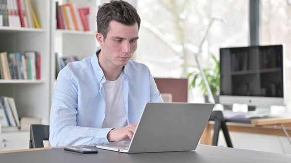 Zajęty młody człowiek pracuje na laptopie — Zdjęcie stockowe