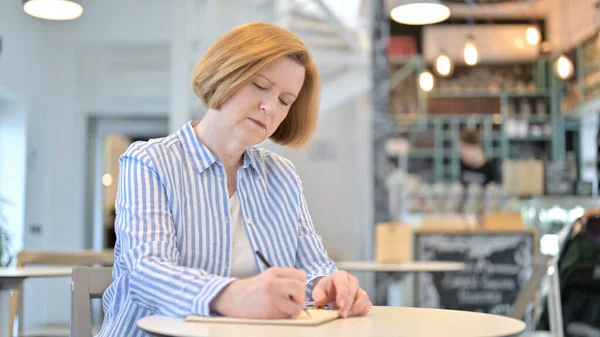 Pensiero creativo vecchia donna facendo scartoffie in Cafe — Foto Stock