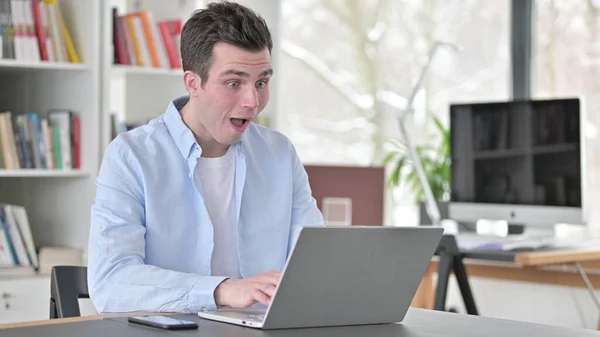 Opgewonden jongeman verrast door resultaten op laptop — Stockfoto