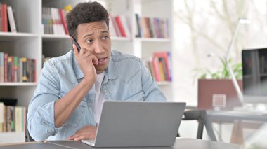 Young African American Man Talking on Smartphone at Work