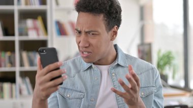 Young African American Man Disappointed by Loss on Smartphone