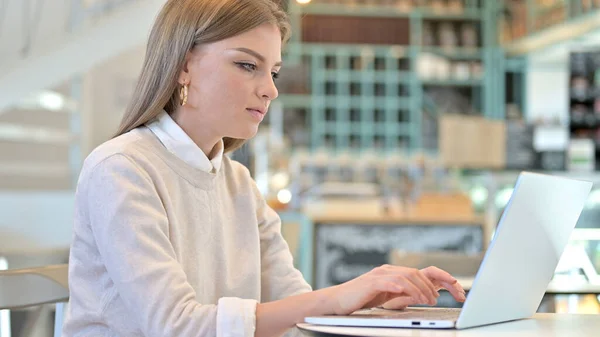 Молода жінка працює на ноутбуці в кафе — стокове фото