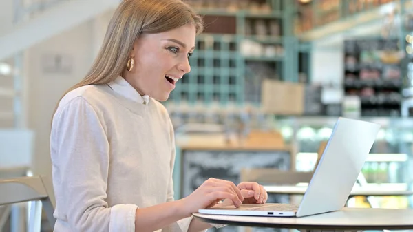Ενθουσιασμένη νεαρή γυναίκα ευτυχής για τα αποτελέσματα στο Laptop στο Cafe, επιτυχία — Φωτογραφία Αρχείου