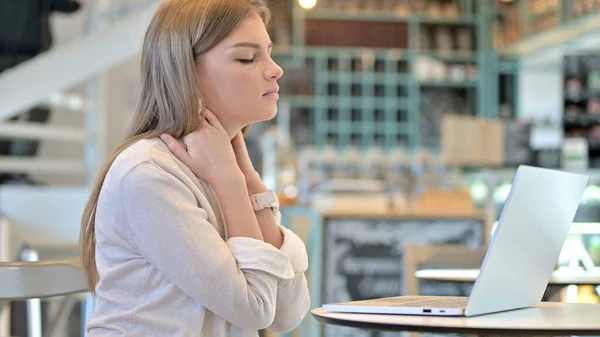 Young Woman with Neck Pain using Laptop in Cafe — Stock fotografie