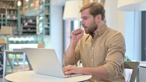 Кашель молодий чоловік використовує ноутбук у кафе — стокове відео