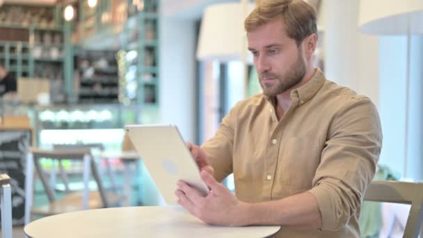 카페에서 디지털 태블릿을 들고 있는 매력적 인 청년 — 비디오