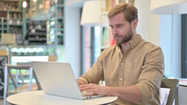 Профессиональный молодой человек с ноутбуком в кафе — стоковое видео