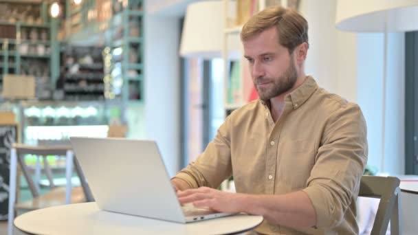 Joven profesional usando el ordenador portátil en Café — Vídeos de Stock