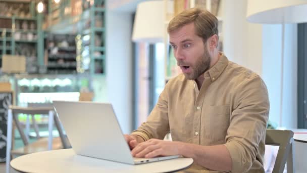 Hombre joven celebrando el éxito en el ordenador portátil en Café — Vídeos de Stock