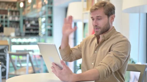 Fešák mladý muž dělá video chat na tabletu v kavárně — Stock video