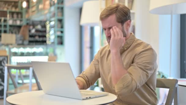 Mladý muž s bolestí hlavy pomocí notebooku v kavárně — Stock video