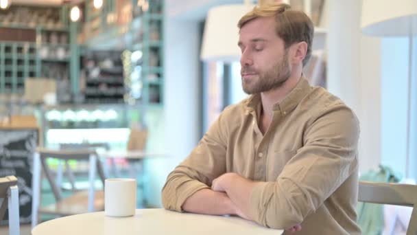 Расслабленный молодой человек пьет кофе в кафе — стоковое видео