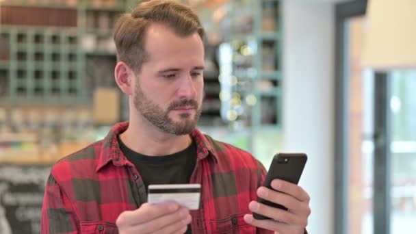 Porträt eines jungen Mannes über das Online-Bezahlen auf dem Smartphone — Stockvideo