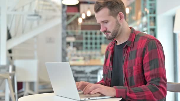 Konzentrierter junger Mann benutzt Laptop in Café — Stockvideo