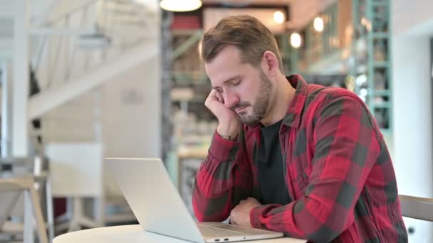 Κουρασμένος νεαρός άνδρας με φορητό υπολογιστή λαμβάνοντας Nap στο καφέ — Αρχείο Βίντεο