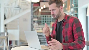 Kafede dizüstü bilgisayar kullanan Dalgın Genç Adam