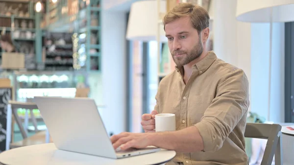 Man Holding Coffee Cup tijdens het werken op laptop — Stockfoto