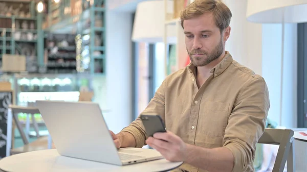 Jongeman met Smartphone en Laptop in Cafe — Stockfoto