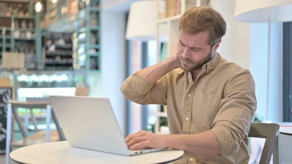 Jeune homme avec douleur au dos à l'aide d'un ordinateur portable dans Cafe — Photo