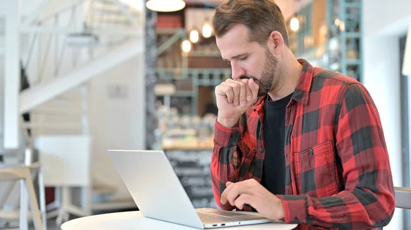 Köhögés szakállas fiatalember segítségével Laptop a Cafe — Stock Fotó