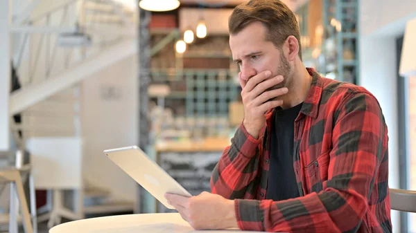 Борода молодой человек разочарован во время использования планшета в кафе — стоковое фото