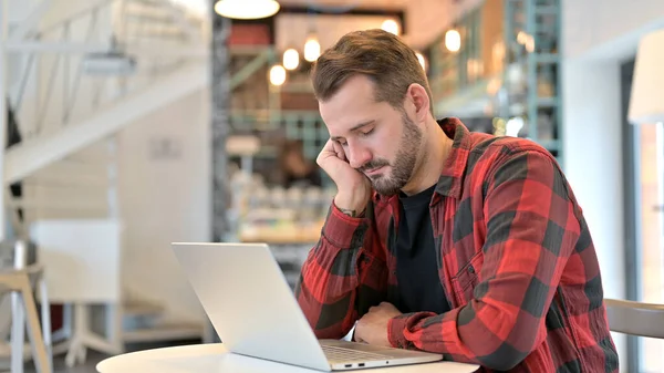 Baard jongeman slapen met laptop in cafe — Stockfoto