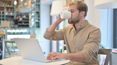 Dizüstü bilgisayarda çalışırken kahve içme adam