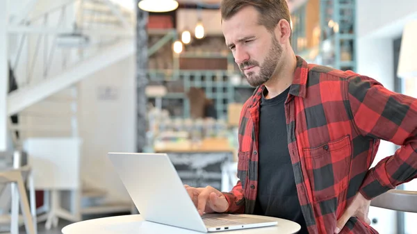 Baard jonge man met rugpijn met behulp van laptop in Cafe — Stockfoto