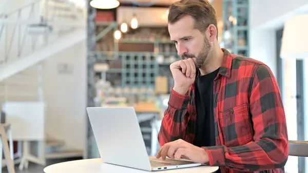 Pensive Beard jonge man lezen op laptop in Cafe — Stockfoto