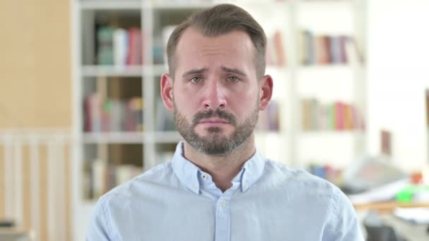 Portret van een droevige jongeman die naar de camera kijkt, van streek — Stockvideo