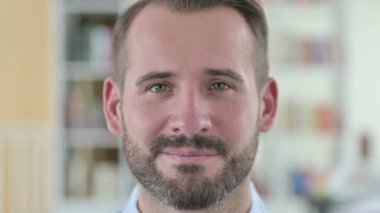 Kameraya gülümseyen genç adama yakın çekim