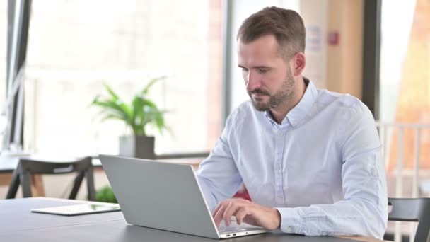 Fröhlicher junger Mann mit Laptop zeigt mit Finger — Stockvideo